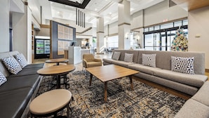 A modern hotel lobby with a sofa, chairs, a coffee table, and a Christmas tree. - Hyatt Place San Antonio-Northwest/Medical Center (San Antonio)