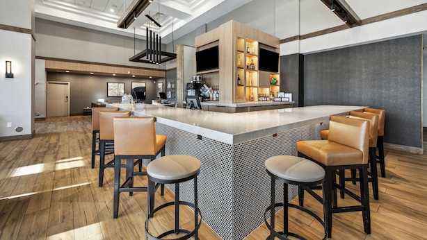 A modern bar area with a central island, bar stools, and a kitchen counter with appliances. - Hyatt Place San Antonio-Northwest/Medical Center (San Antonio)