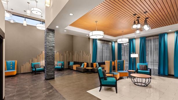 Een moderne lobby met zithoeken, een accentmuur van steen en een houten plafond.