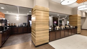 Een moderne hotel lobby met een receptiebalie, een koffiehoek en een zithoek.