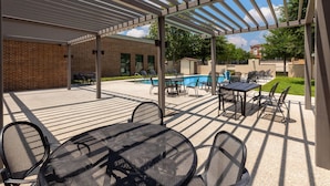 Eine Außenpatio mit Pergola, Pool und Sitzbereich.