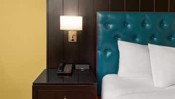 A hotel room with a bed, a nightstand with a lamp, a phone, and a drawer.