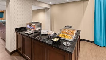 A breakfast bar with a coffee machine, bread, and fruit display.