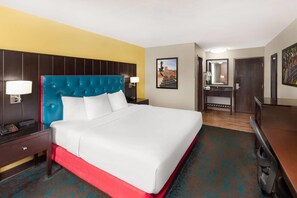 Une chambre d’hôtel avec un lit, une table de chevet, une lampe et un miroir.