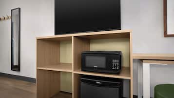 A compact kitchenette with a microwave, a dishwasher, and a blackboard on the wall.