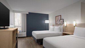 A hotel room with two beds, a TV, a desk, and a window with curtains. - Spark by Hilton Denver East I 70 (Denver)