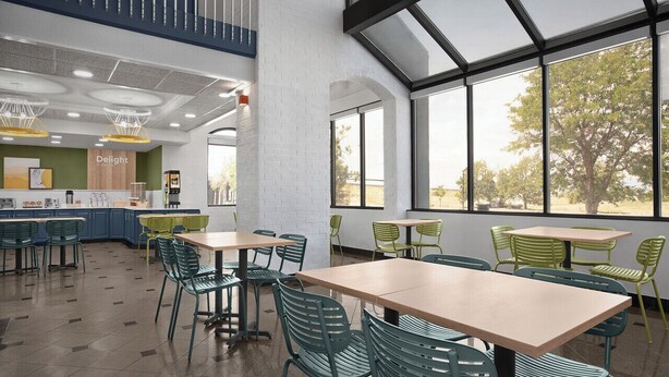 A modern dining area with green chairs and tables, a counter with a sign reading "Delight," and large windows offering a view of trees. - Spark by Hilton Denver East I 70 (Denver)