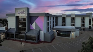 A modern hotel with a geometric facade, large windows, and a parking lot. - Spark by Hilton Denver East I 70 (Denver)