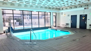 An indoor swimming pool with clear markings, a lifeguard chair, and a view of the outside through large windows. - Spark by Hilton Denver East I 70 (Denver)