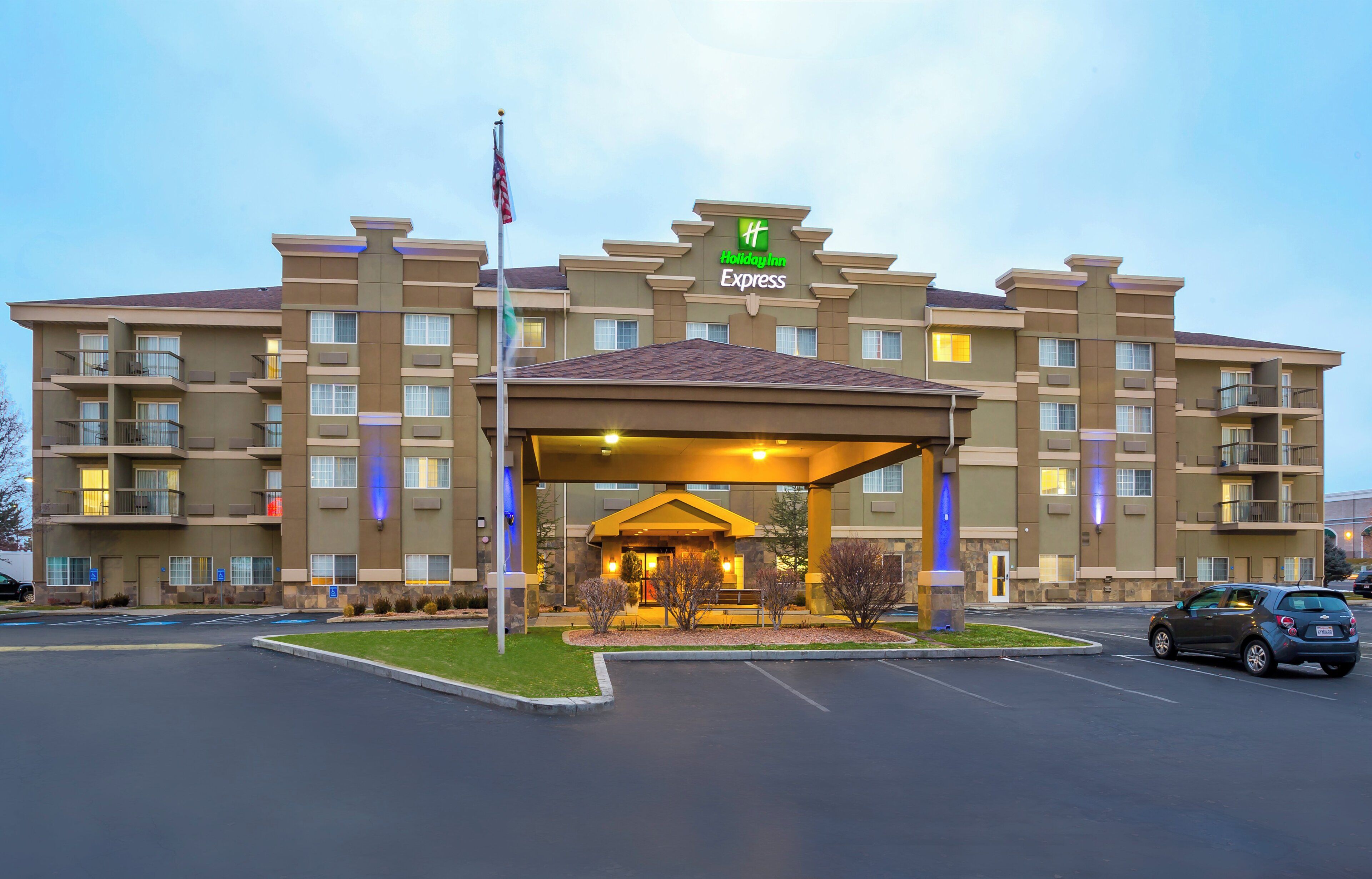 Un hotel Holiday Inn Express con entrada cubierta, varios balcones y un asta de bandera.