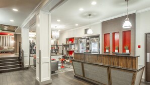 Une cuisine moderne dotée d’un îlot central, d’appareils électroménagers intégrés et d’un mur d’accent rouge.