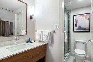 Une salle de bain moderne avec un lavabo en marbre, un meuble-lavabo en bois, une cabine de douche en verre et des toilettes.