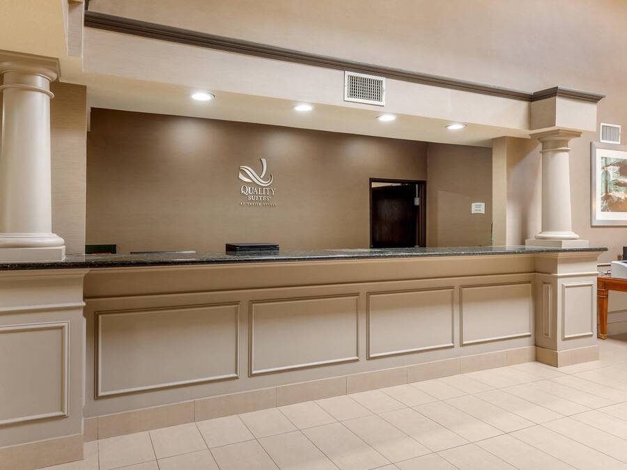 A reception desk with a logo, a door, and a trash can.