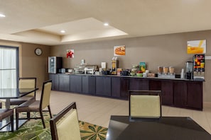 Un área de desayuno de hotel con mostrador, asientos y un reloj.