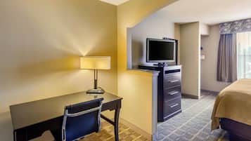 A hotel room with a desk, chair, television, and a bed.