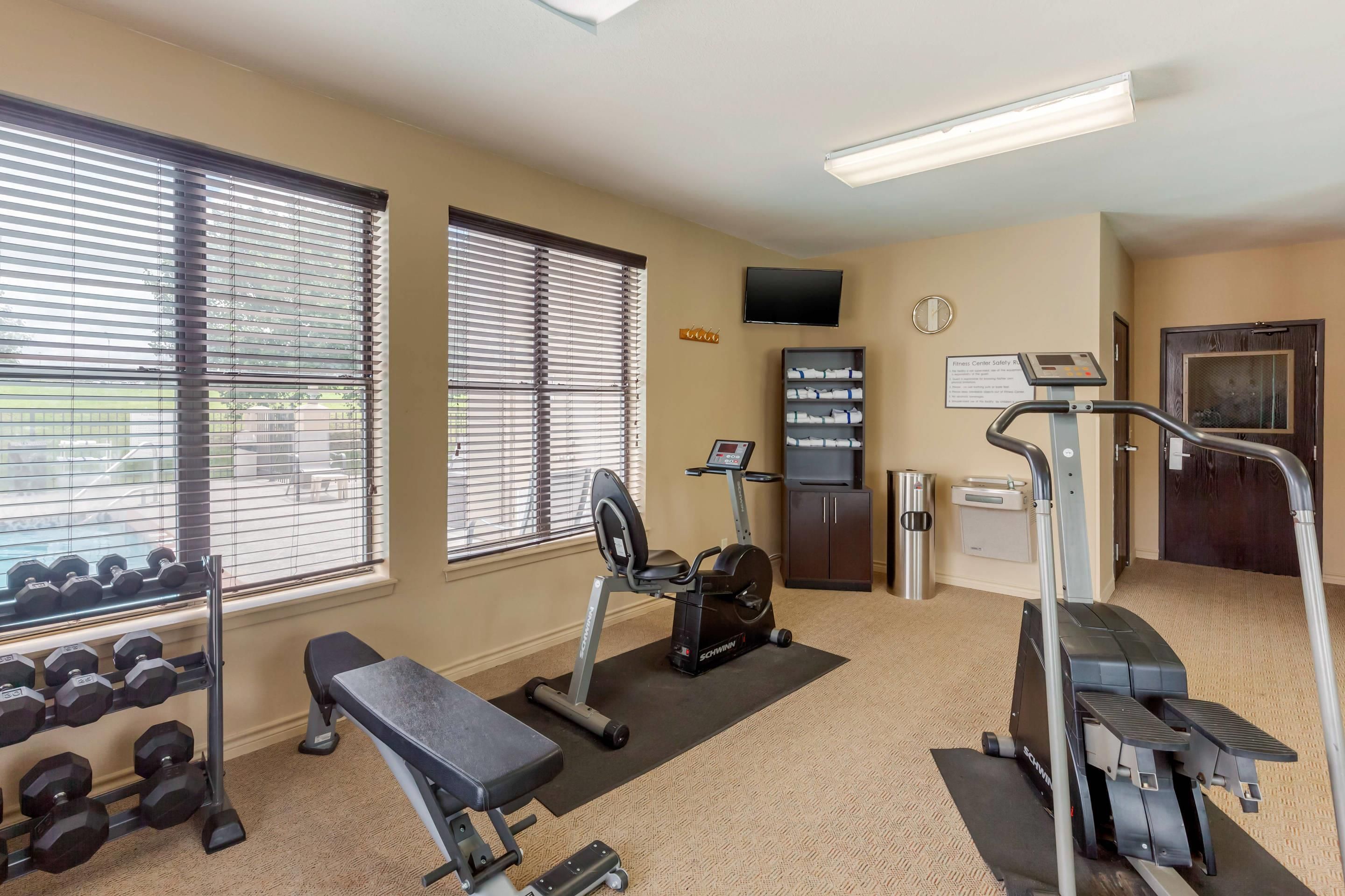 A gym with exercise equipment, dumbbells, and a television.