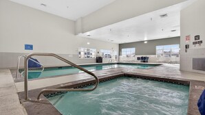 A swimming pool area with clear water, metal pool ladders, and a tiled floor. - Best Western Timpanogos Inn (Lehi)