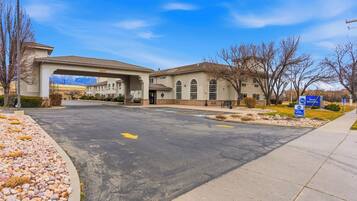 A building with a covered entrance, a parking lot, and a sign indicating 'Best Western' hotel.