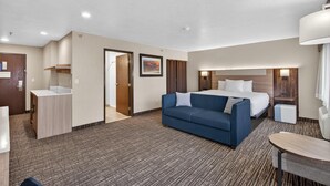 A hotel room with a bed, a blue sofa, a desk, and a small table. - Best Western Timpanogos Inn (Lehi)