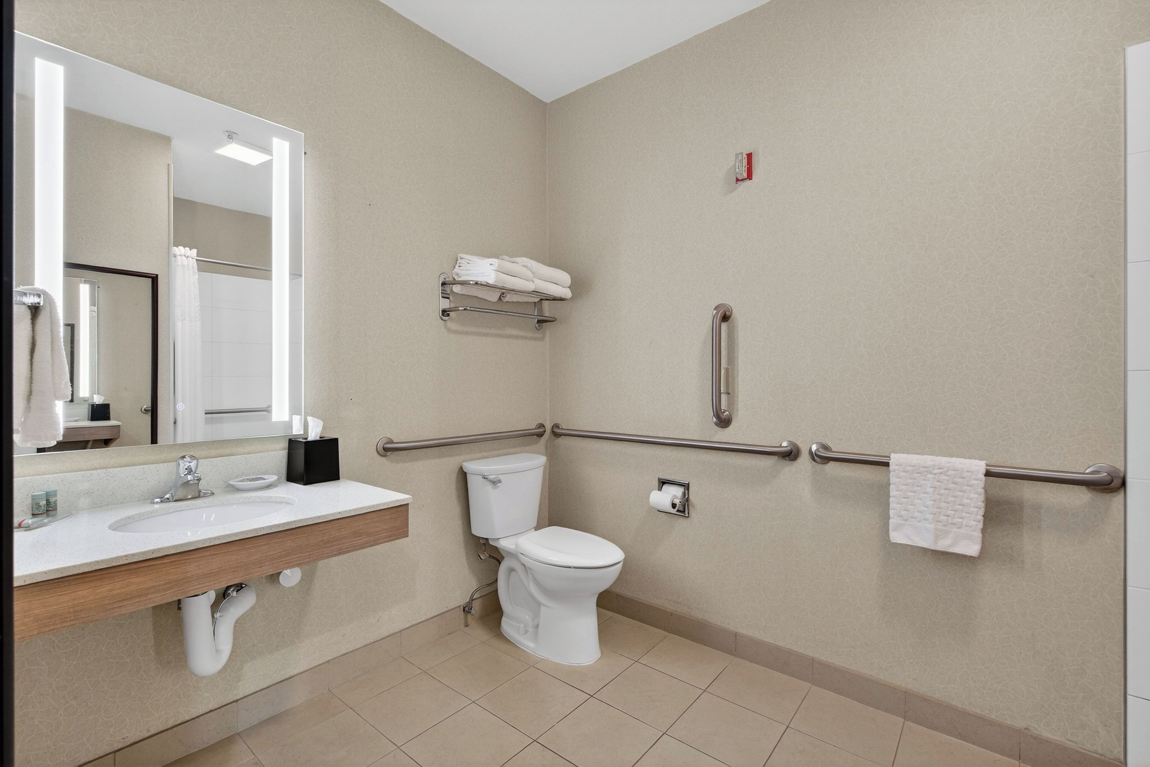 Een moderne badkamer met een wastafel, toilet en handgrepen.