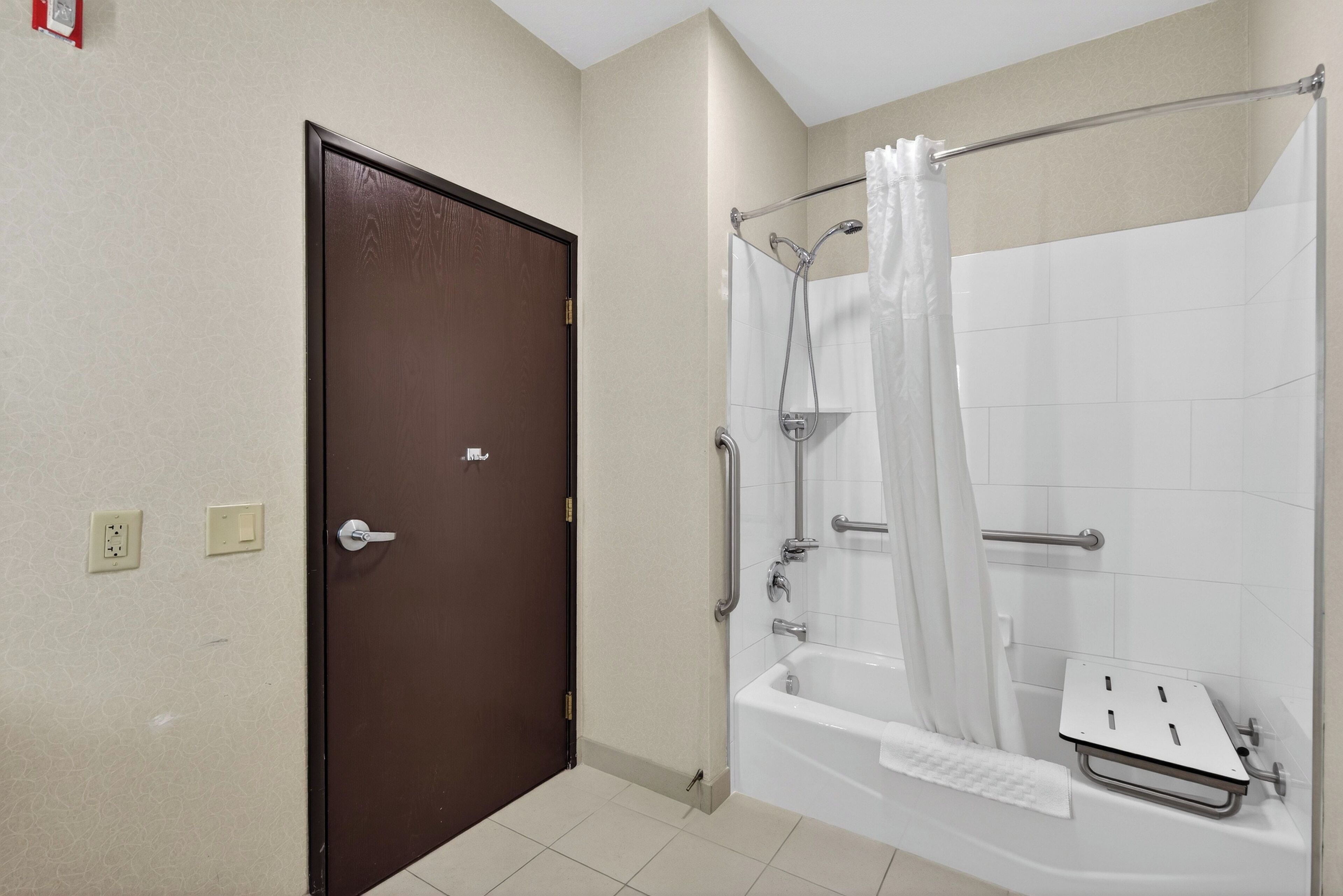 Un baño con ducha, bañera, puerta y perchero.
