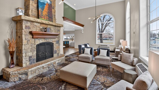 A spacious living area with a stone fireplace, comfortable seating, and large windows offering views. - Best Western Timpanogos Inn (Lehi)