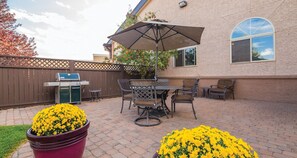 A patio with a grill, outdoor furniture, and potted yellow flowers. - Best Western Plus Deer Park Hotel & Suites (Craig)