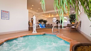 Une piscine intérieure agrémentée d’une fontaine, entourée de chaises longues et de plantes en pot.