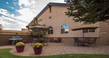 A patio area with outdoor furniture, a grill, and potted plants.