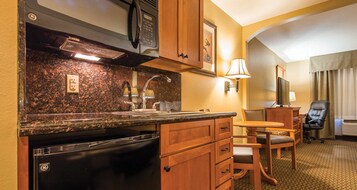 A compact kitchen with granite countertops, a built-in oven, and wooden cabinetry. There is a small dining area with a table and chairs.