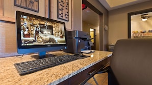 A desktop computer with a monitor displaying a bear, a printer, and a keyboard on a granite countertop.