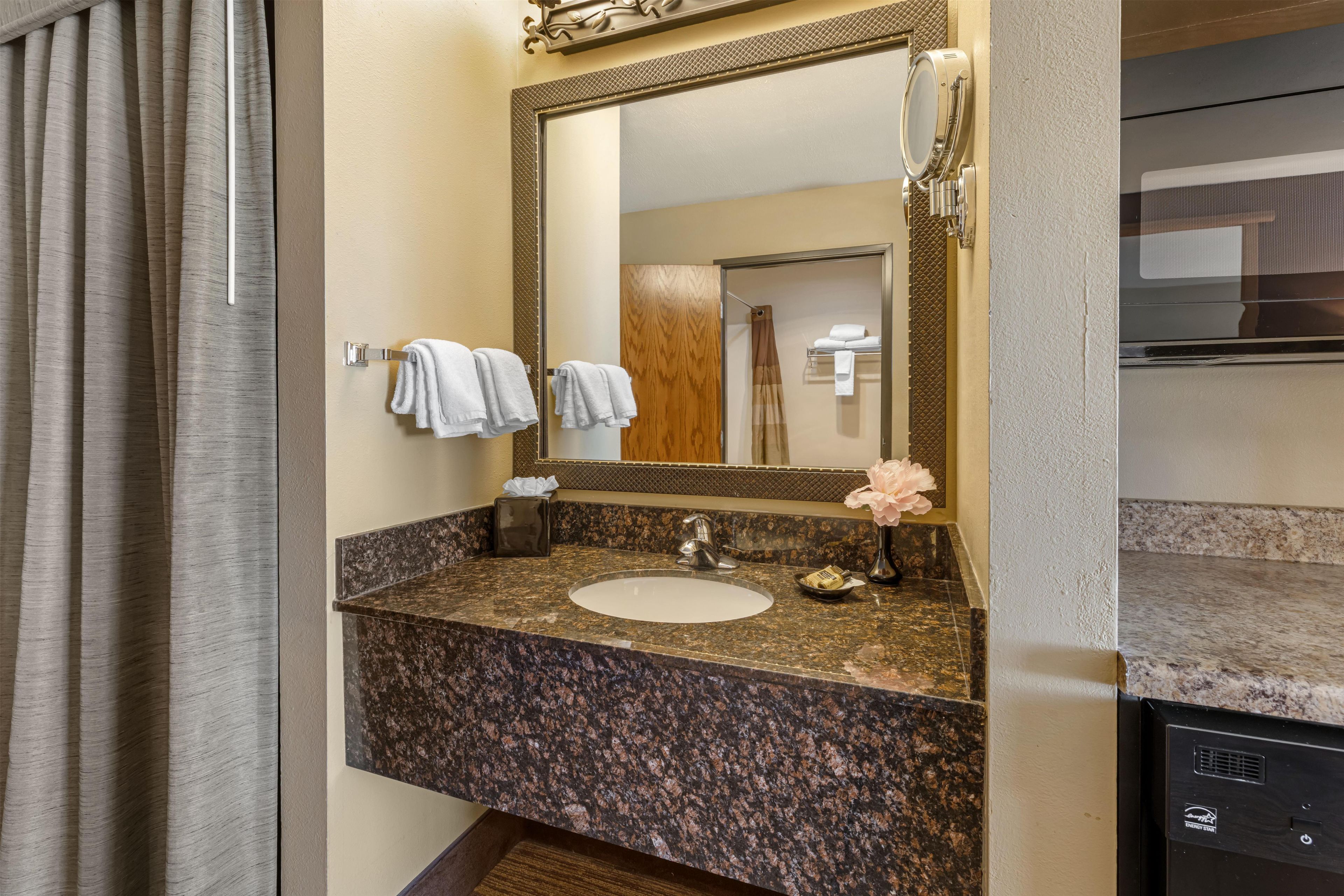 Une salle de bain avec un comptoir en granit, un lavabo, un miroir et un porte-serviettes.