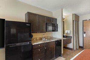 A compact kitchen with a refrigerator, microwave, and sink.