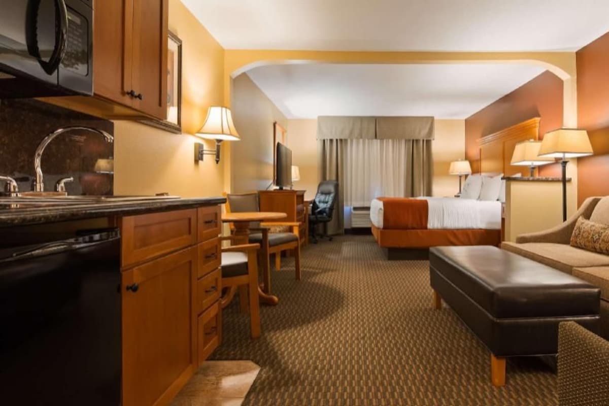 Una habitación de hotel con kitchenette, cama, sofá, escritorio y televisor.