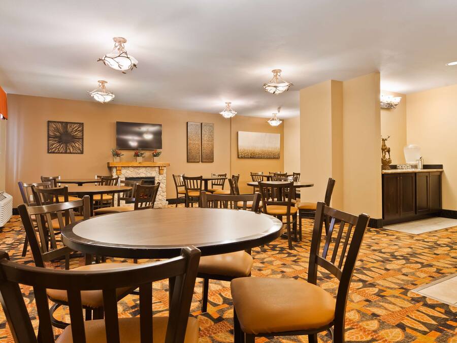 A conference room with a round table, multiple chairs, a fireplace, and artwork on the walls.