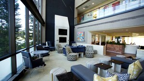 A spacious lobby with modern furniture, large windows, and a mezzanine level.