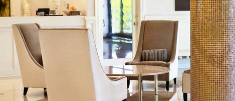 A modern lobby with two armchairs, a coffee table, and a tiled column.