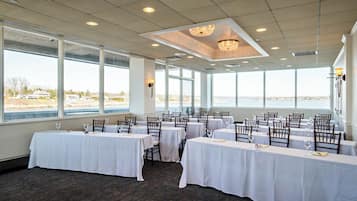 A dining area with tables set for a meal, large windows, and a view of the outdoors.