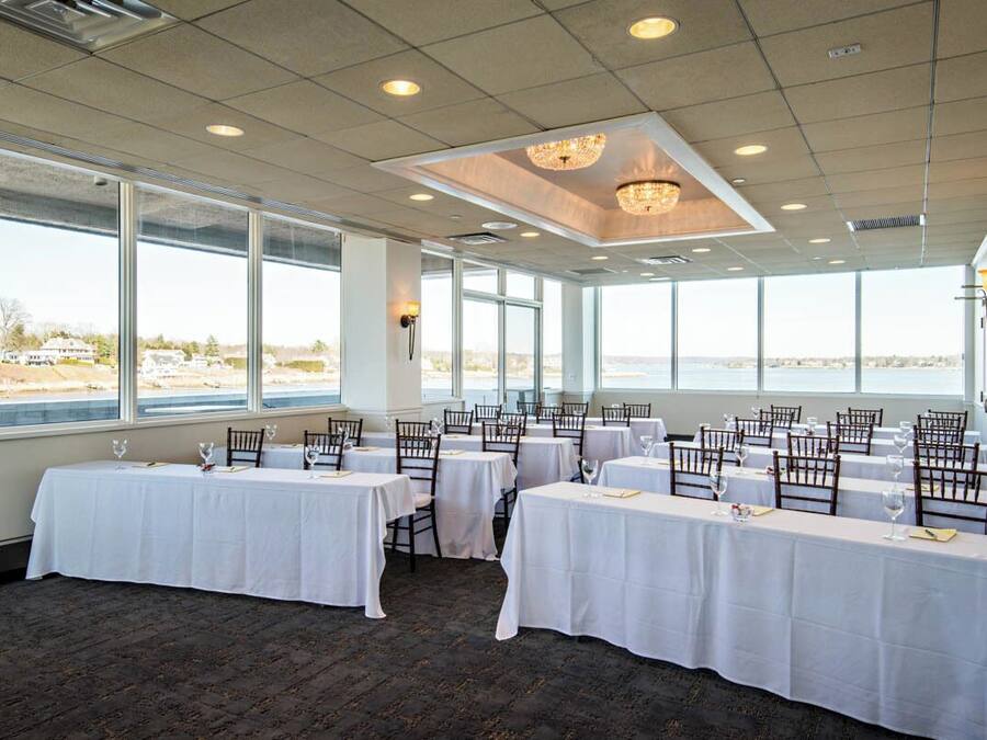 A dining area with tables set for a meal, large windows, and a view of the outdoors.