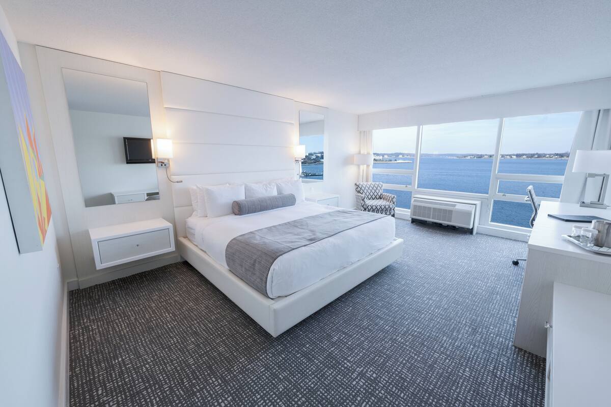 Ein modernes Hotelzimmer mit einem großen Bett, einem Schreibtisch und Meerblick.