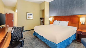 A hotel room with a bed, a desk, a chair, a television, and a wardrobe.
