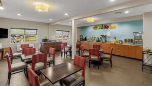 Un restaurante con cabinas y mesas, un área de cocina y vistas al exterior.