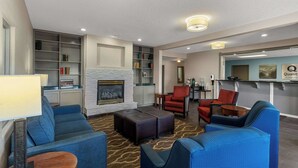 Un vestíbulo de hotel moderno con chimenea, zona de estar y mostrador de recepción.