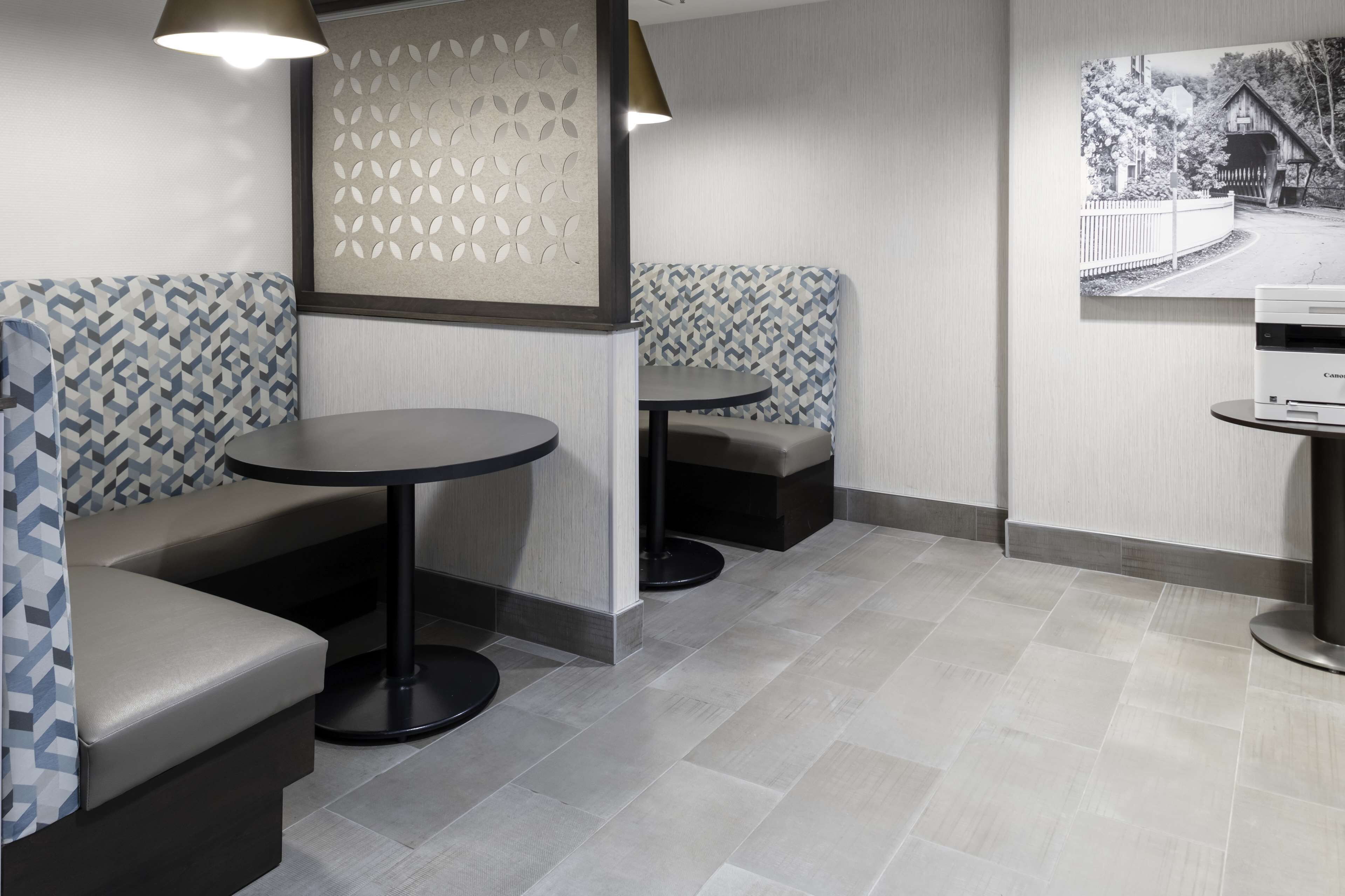 A modern interior with seating areas, a round table, and a printer on the wall.