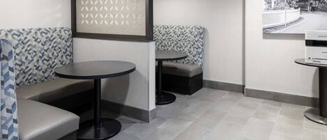 A modern interior with seating areas, a round table, and a printer on the wall.