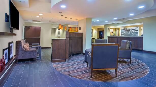 A hotel lobby with a reception desk, seating area, and a television mounted on the wall. - Hampton Inn Conyers (Conyers)
