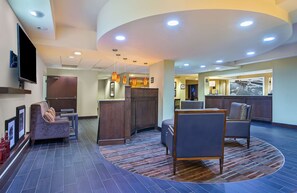 A hotel lobby with a reception desk, seating area, and a television mounted on the wall. - Hampton Inn Conyers (Conyers)