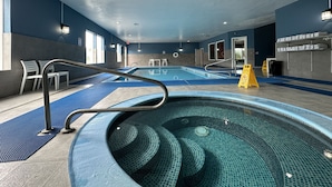 A large indoor swimming pool with a clear water view, surrounded by blue walls and a tiled floor. - BayVue Hotel, Resort and Suites (Ocean Shores)