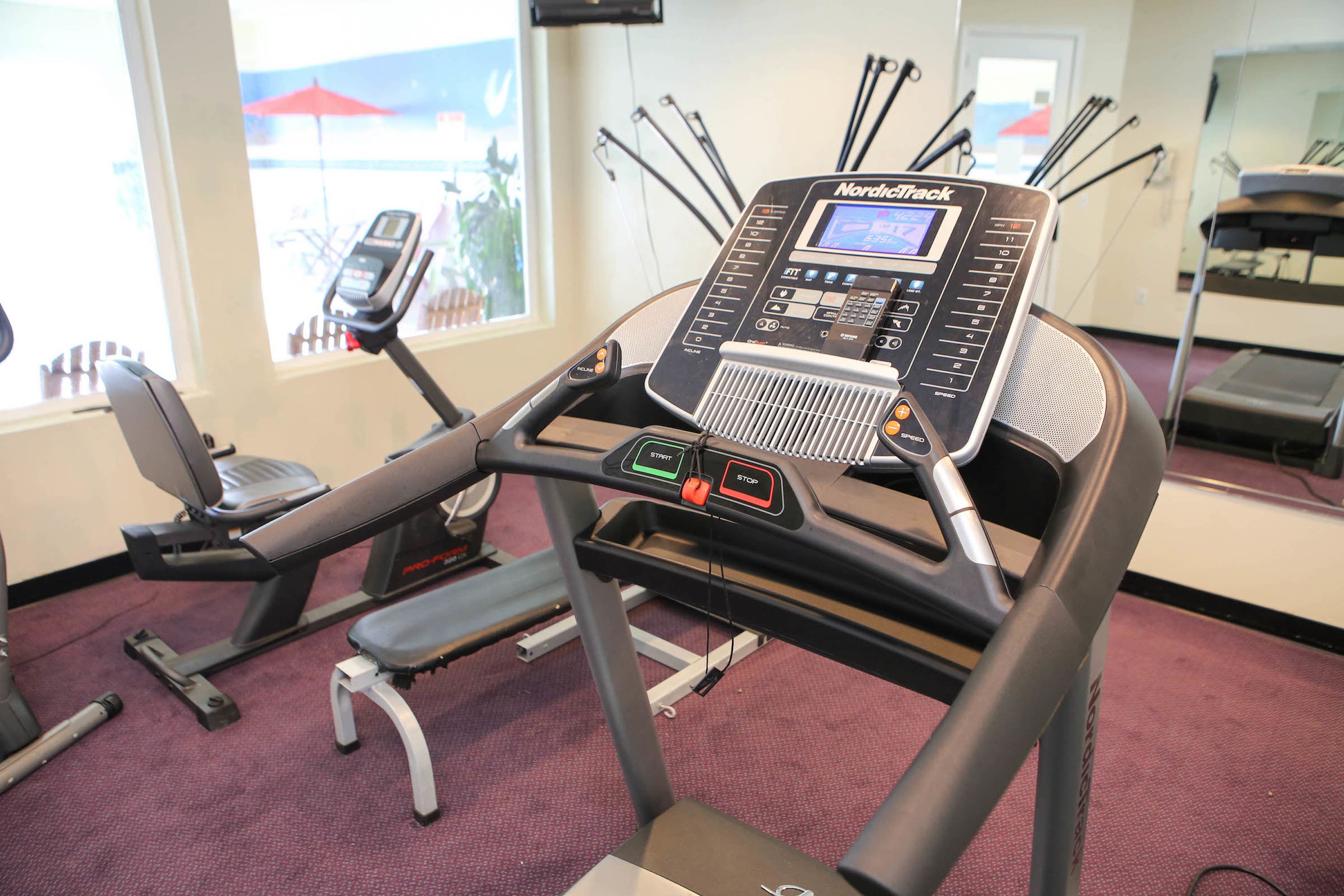 A treadmill with a digital display, control panel, and a step platform.