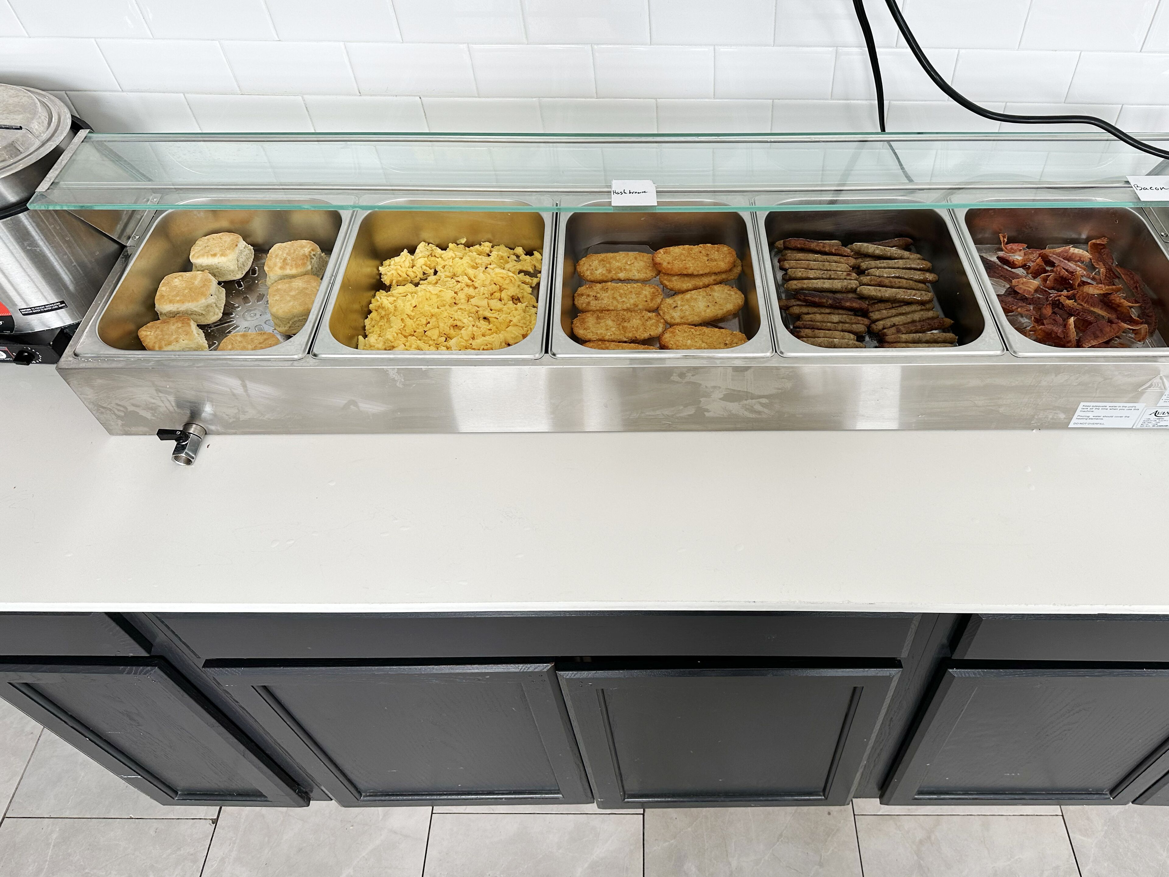 A buffet with various food items including biscuits, scrambled eggs, croquettes, and bacon.